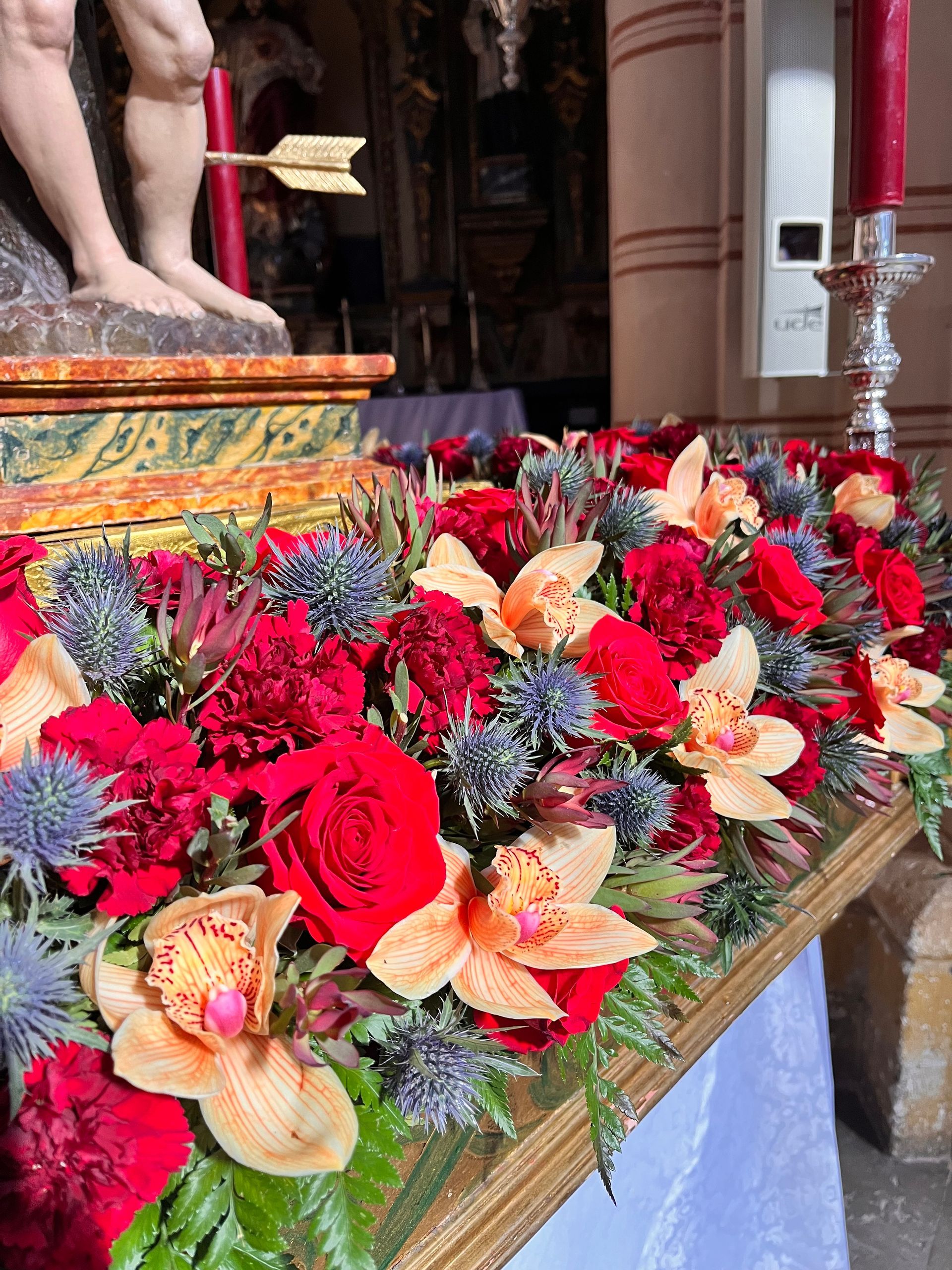 Una estatua de Jesús está rodeada de flores y velas.