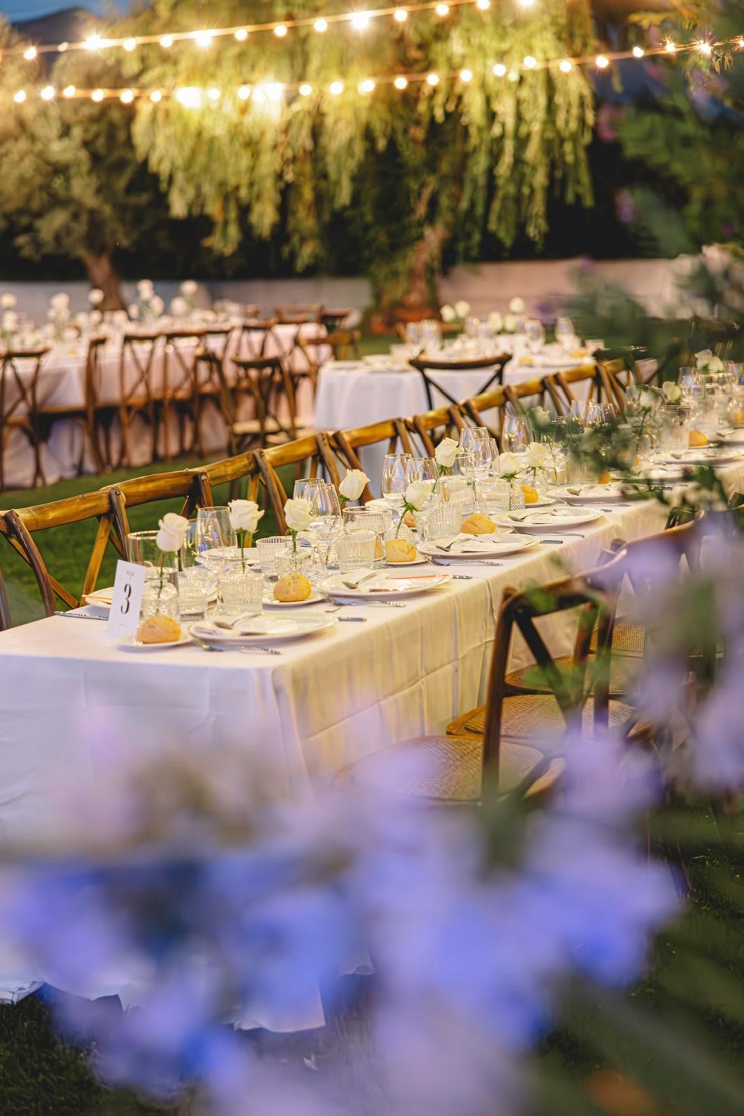 Una mesa larga preparada para una recepción de boda con flores en primer plano.