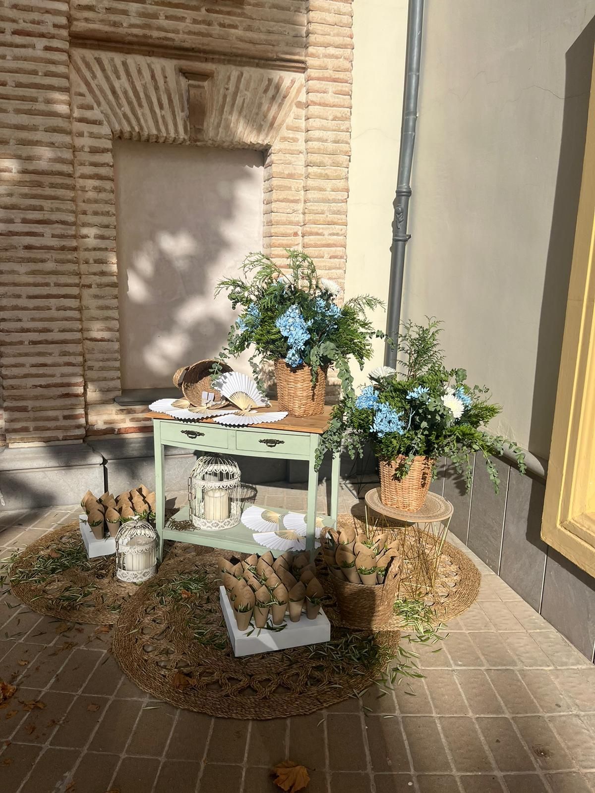 Una mesa con flores delante de un edificio de ladrillos.