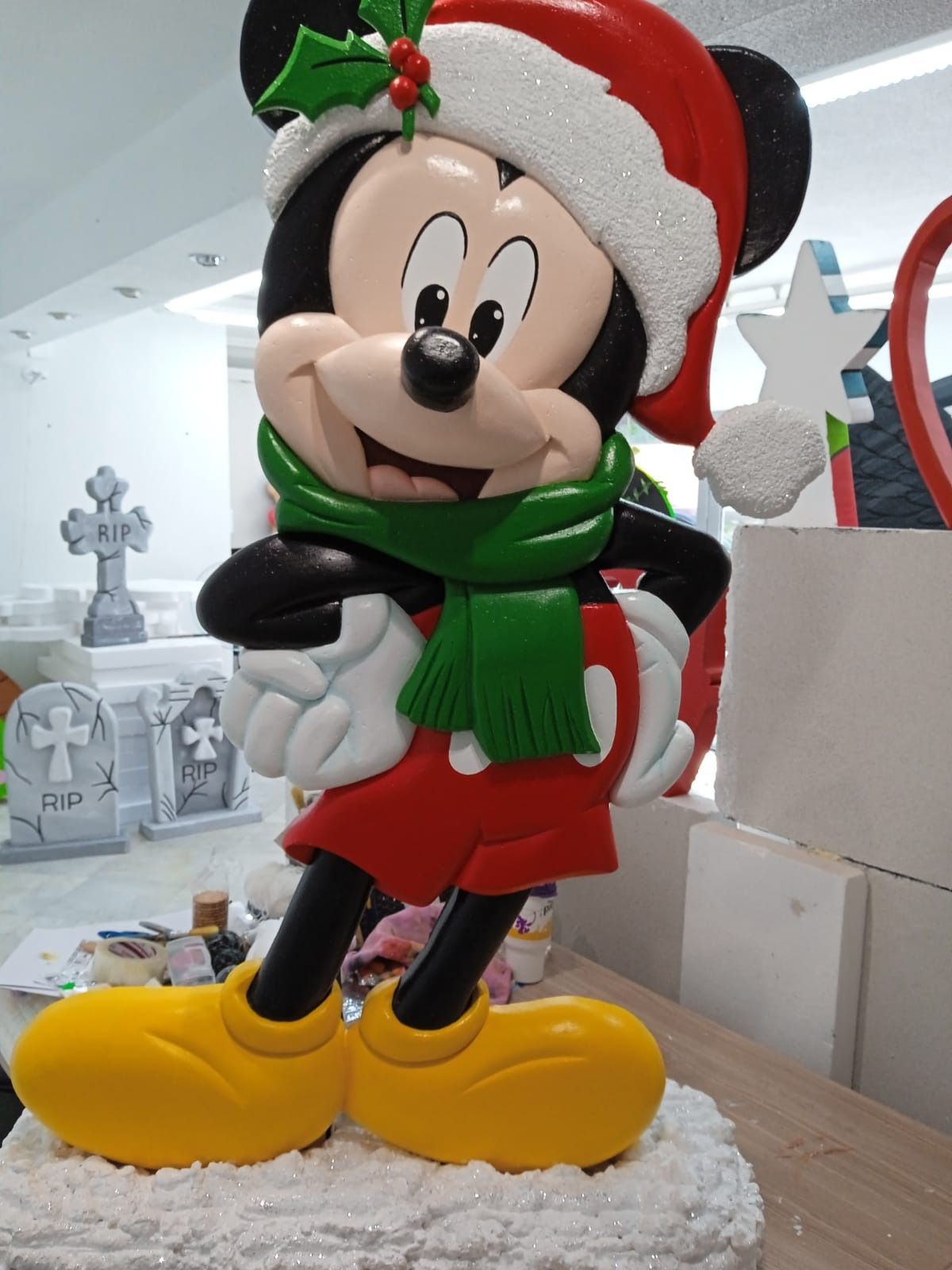 Una estatua de Mickey Mouse con un gorro y una bufanda de Papá Noel.