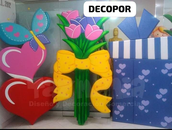 Un ramo de flores en un jarrón con un lazo amarillo se encuentra junto a una caja de regalo.
