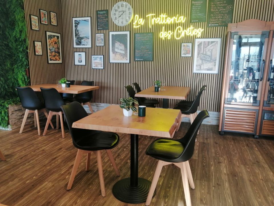 Un restaurant avec des tables et des chaises et une enseigne au néon qui dit la trattoria