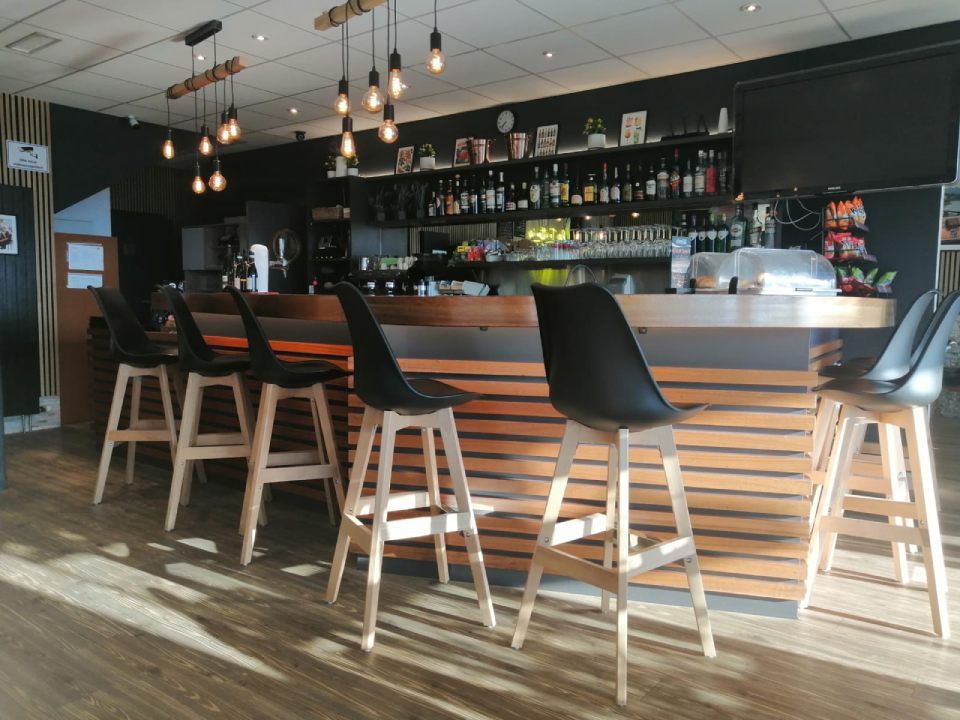 Une rangée de tabourets de bar sont alignés devant un bar dans un restaurant.