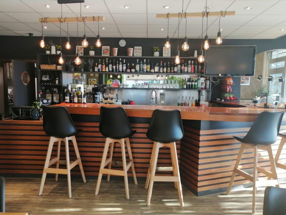 Un restaurant avec un bar et des tabourets devant