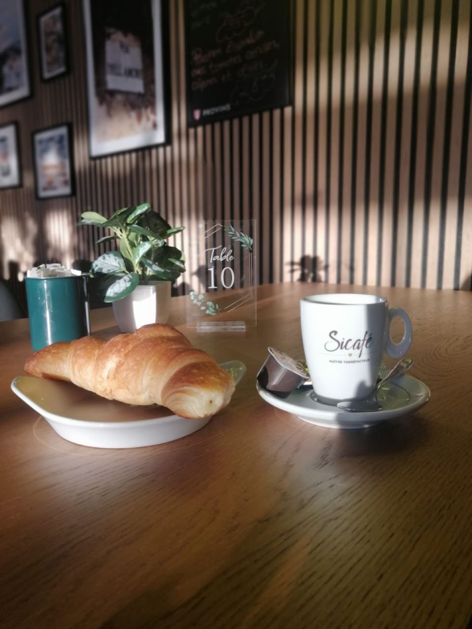 Un croissant et une tasse de café sont sur une table en bois.