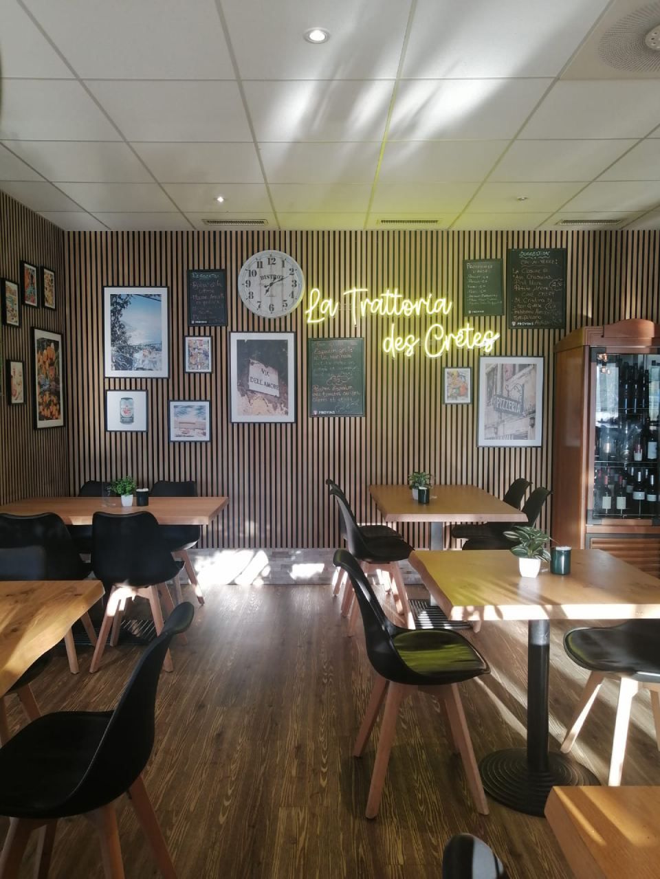 Un restaurant avec des tables et des chaises et une enseigne au néon qui indique trattoria dessus