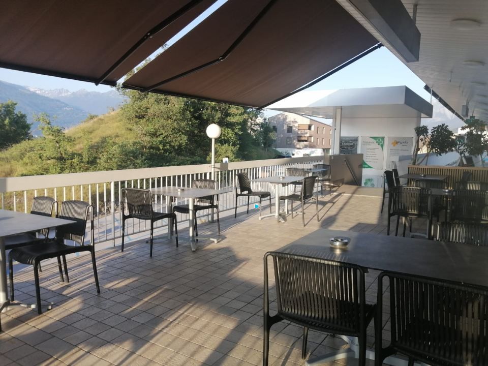 Un patio avec tables et chaises sous un auvent