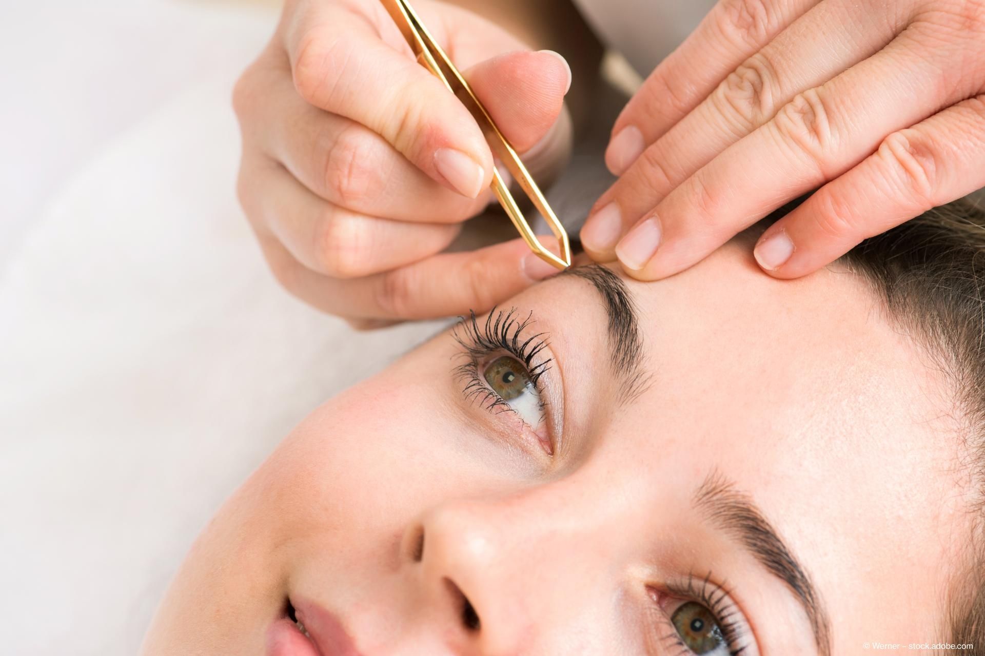 A close-up of hands applying makeup with a brush, showcasing a careful and artistic application process.