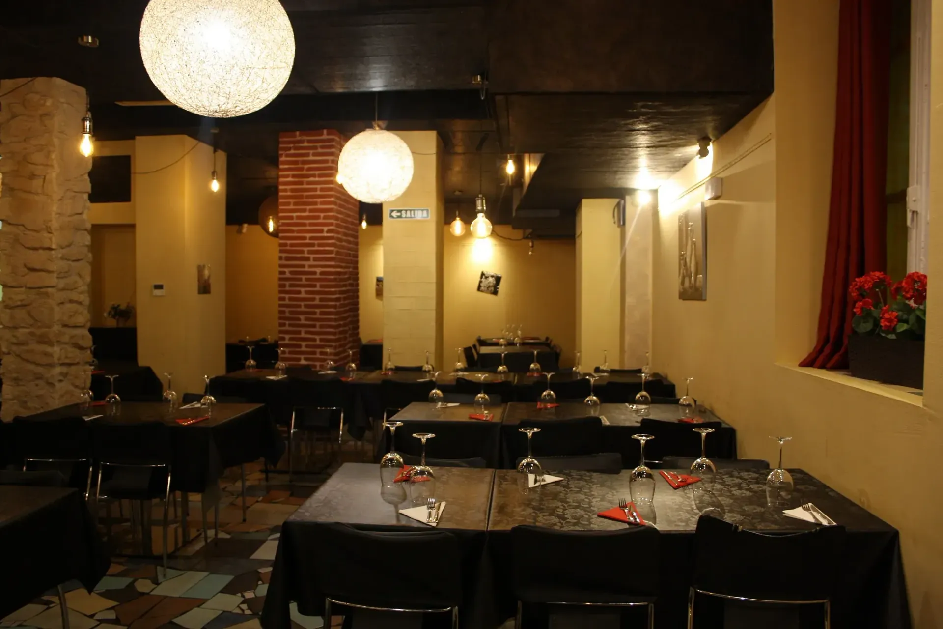 Un restaurante lleno de mesas y sillas con vasos sobre ellas.
