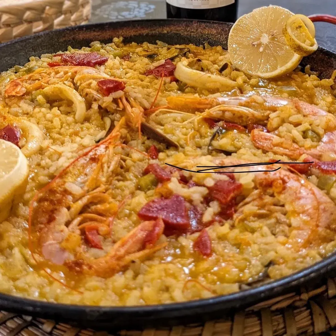 Una sartén llena de arroz, camarones y rodajas de limón.