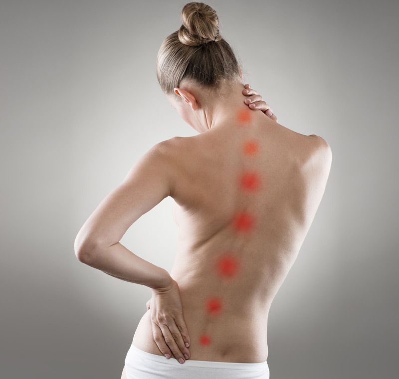 Una mujer se sostiene la espalda con dolor.