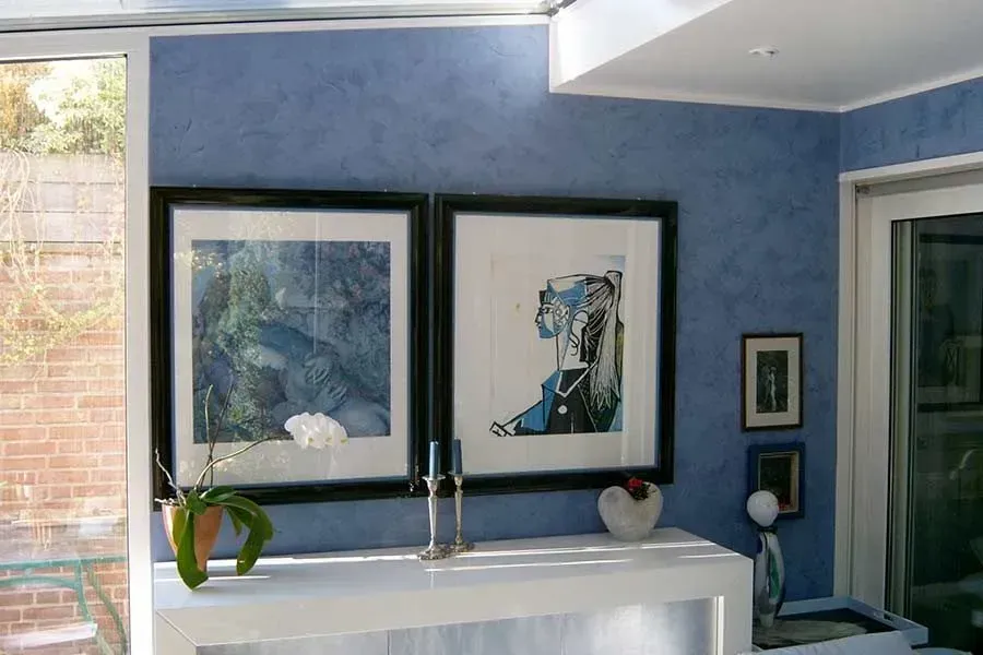 Blaue Spachteltechnik an einer Wand mit Bildern