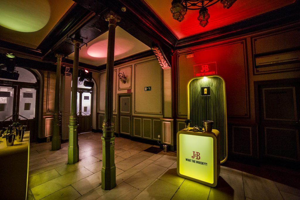 Elegante recibidor con molduras ornamentadas, luces rojas en el techo y un letrero luminoso sobre un suelo pulido.