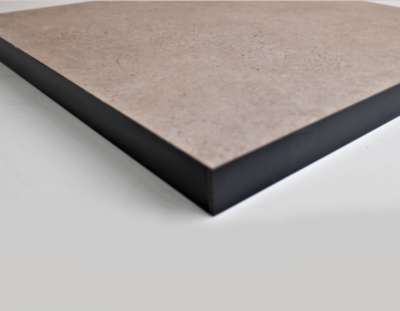 Primer plano de un tablero cuadrado con una superficie superior de color marrón claro y bordes negros, en ángulo sobre una superficie blanca.