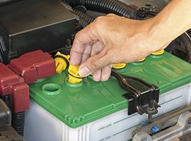 Una persona está conectando una batería verde a un automóvil.
