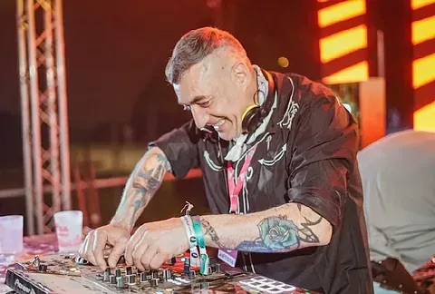 Un hombre con tatuajes está tocando música en un mezclador en un escenario.