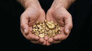 Deux mains tenant un tas de pépites d'or sur fond noir