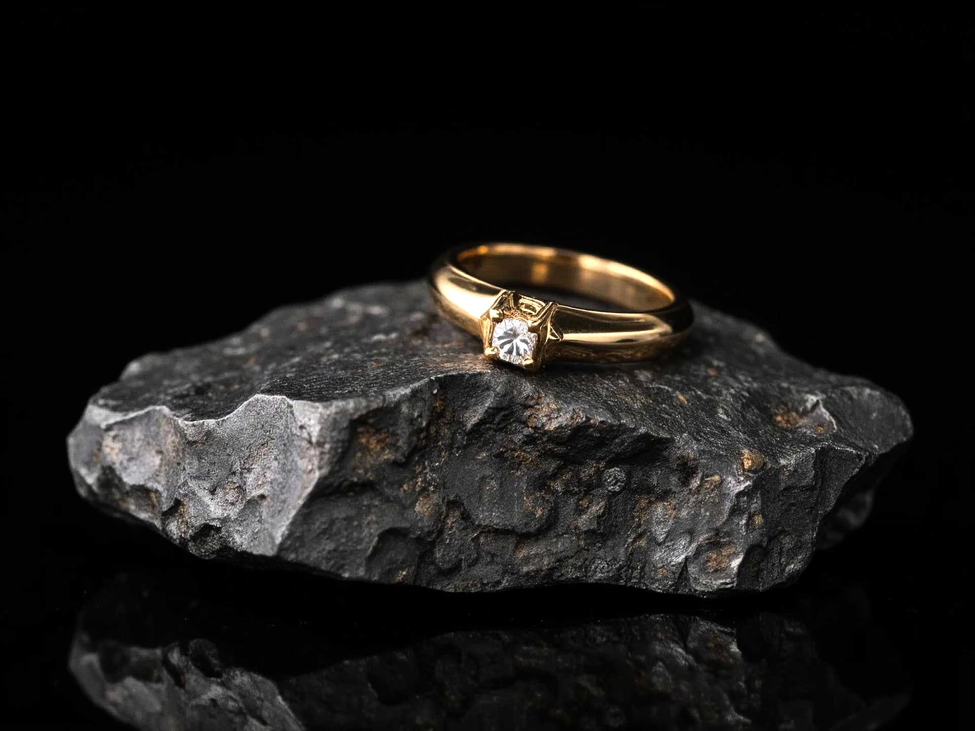 Bague en or avec une pierre précieuse transparente posée sur une roche sombre sur fond noir