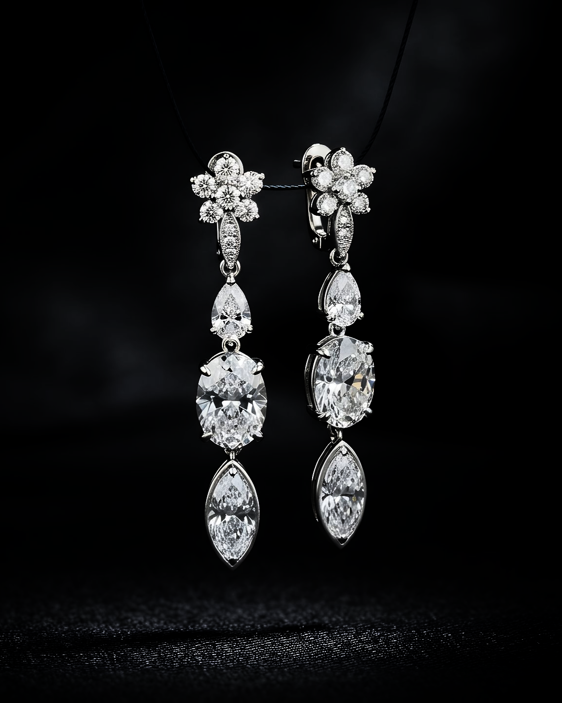 Paire de boucles d'oreilles pendantes en diamant sur fond noir.