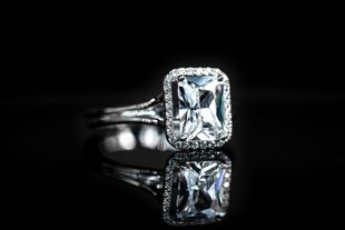 Bague en argent avec une pierre précieuse rectangulaire transparente sur fond noir réfléchissant
