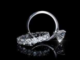 Bague de fiançailles en diamant sur fond noir, avec une grosse pierre centrale ronde et un anneau étincelant.