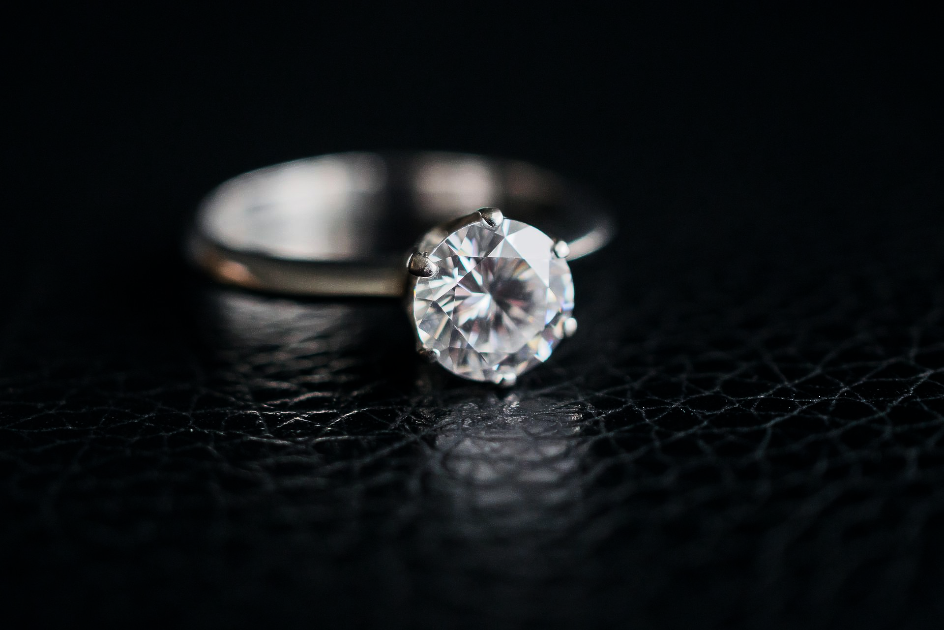 Bague en diamant sur une surface texturée sombre avec une bande floue en arrière-plan.
