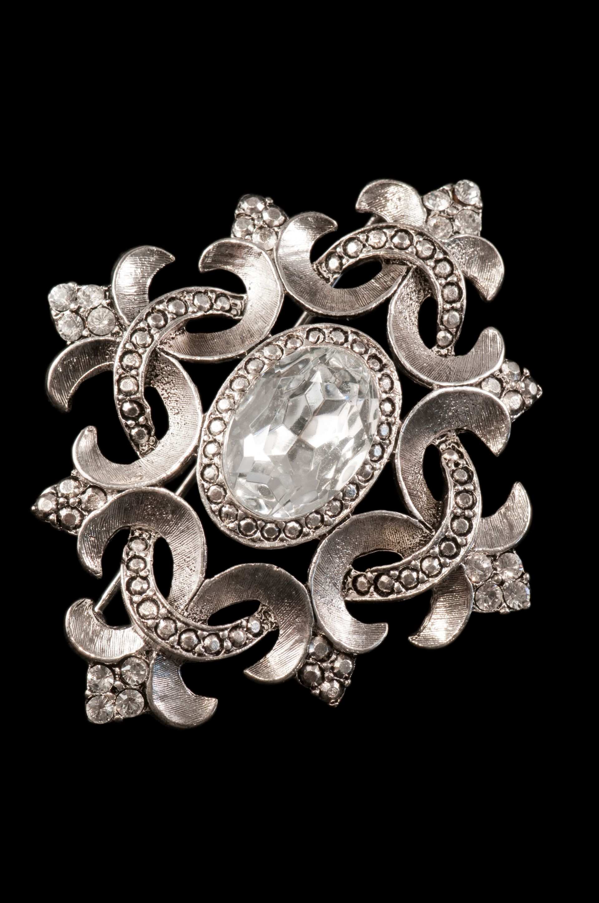 Broche florale en argent avec une pierre précieuse ovale transparente au centre sur fond noir