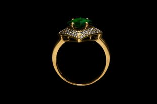 Bague en or ornée d'une pierre précieuse verte et de diamants sur fond noir