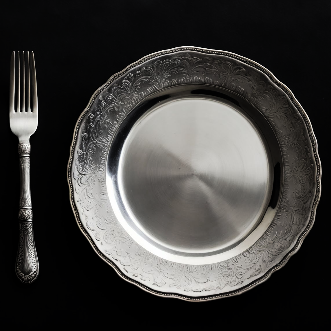 Assiette et fourchette en argent sur fond noir, vue de dessus