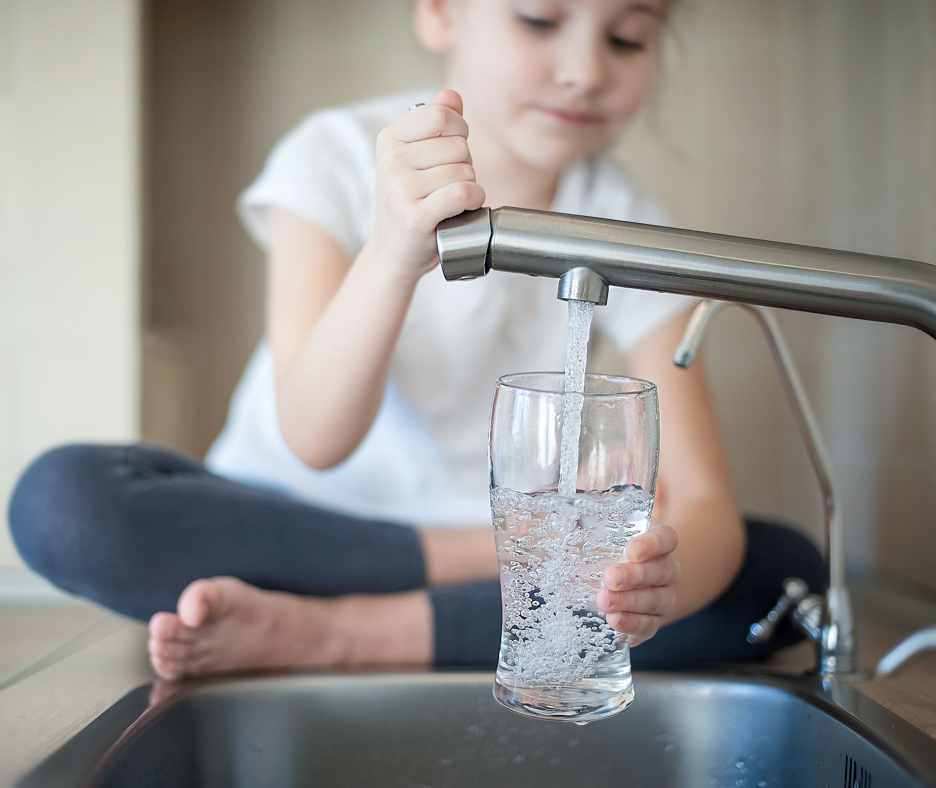 Petite fille se servant de l'eau au robinet
