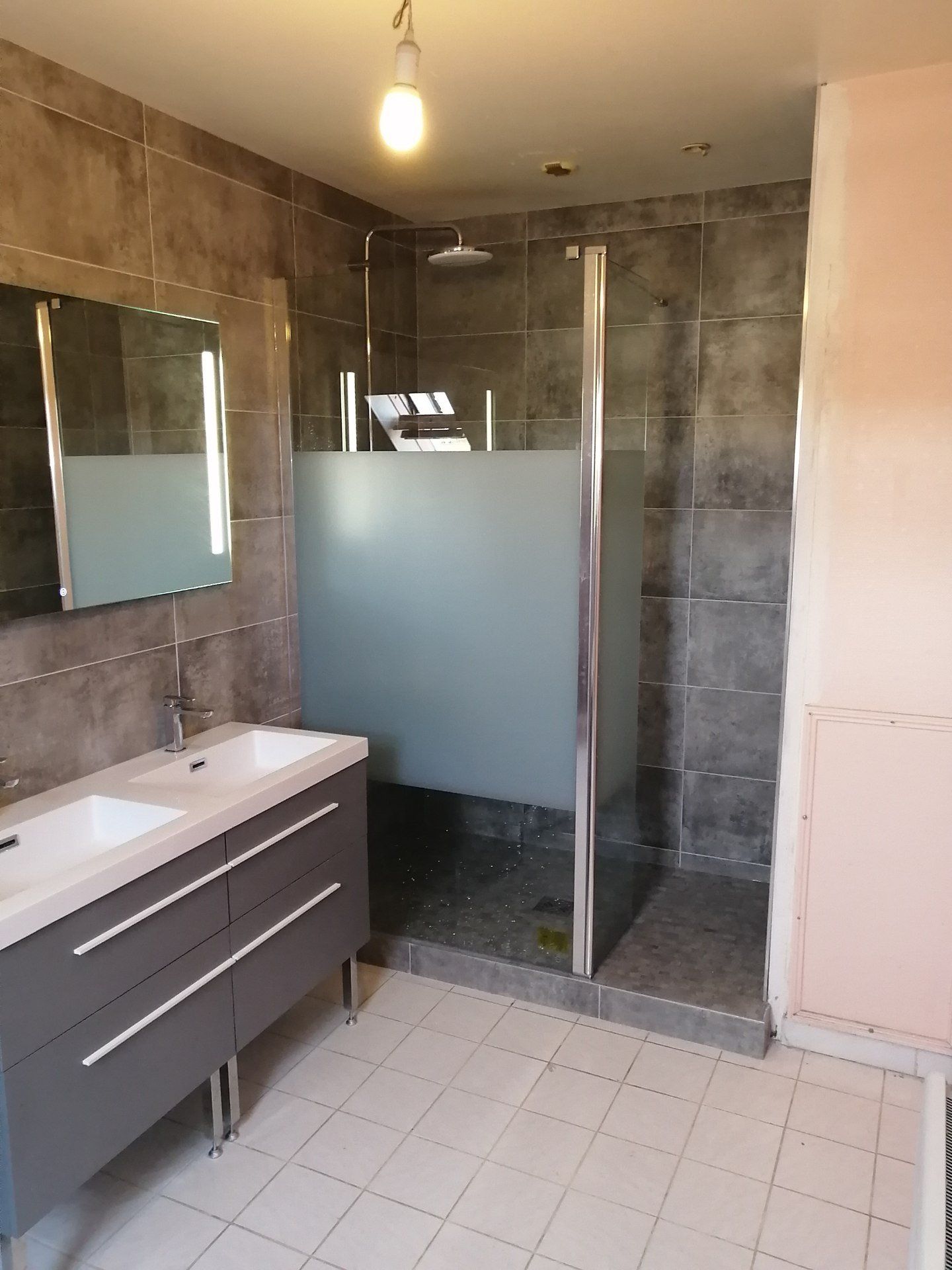 Salle de bains modernisée avec douche et carrelage gris