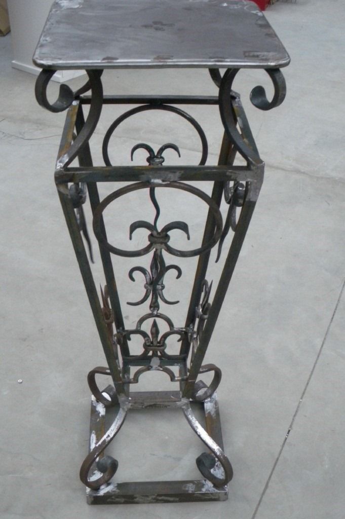 Support à plantes en métal avec plateau et base carrés, orné de motifs de fleur de lys.