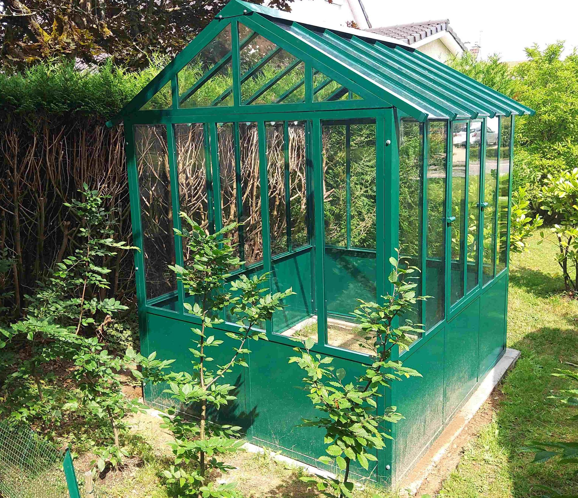 Une serre en fer forgé vert dans un jardin