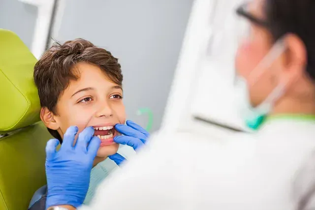 Un niño pequeño está sentado en una silla dental mientras un dentista le examina los dientes.