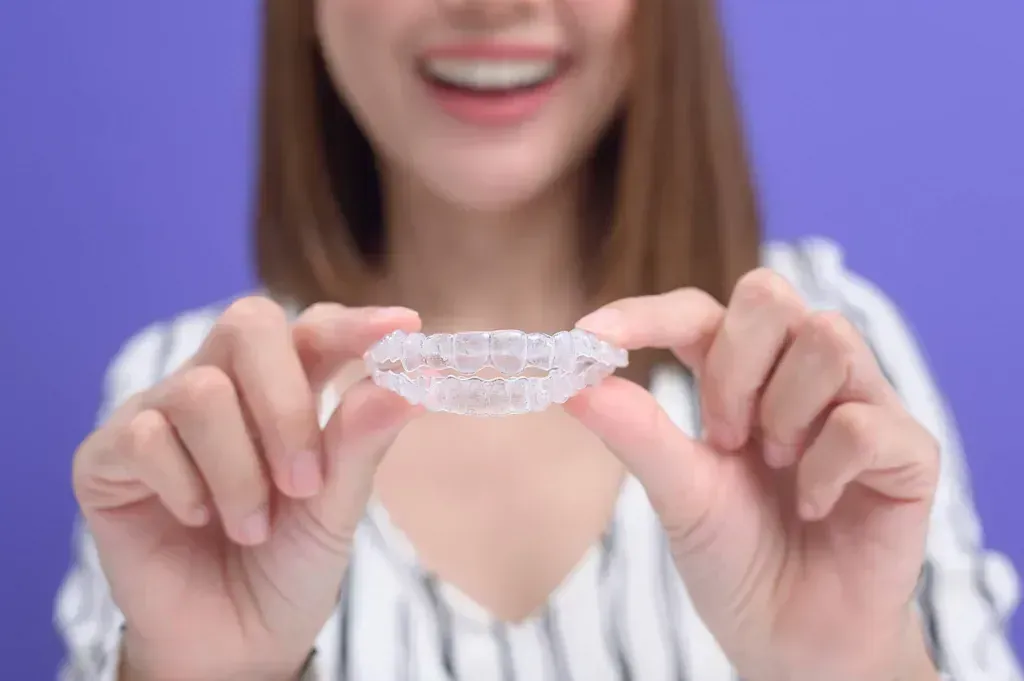 Una mujer sostiene un aparato ortopédico transparente en sus manos.