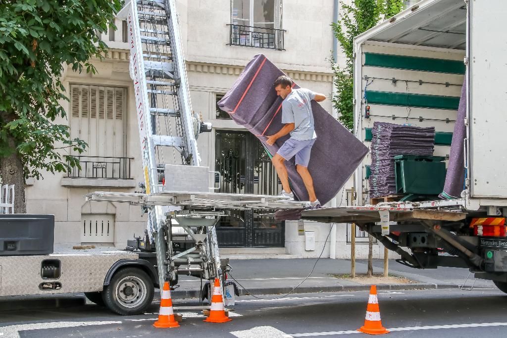 Homme qui réceptionne un meuble emballé à l'aide d'un monte-charges