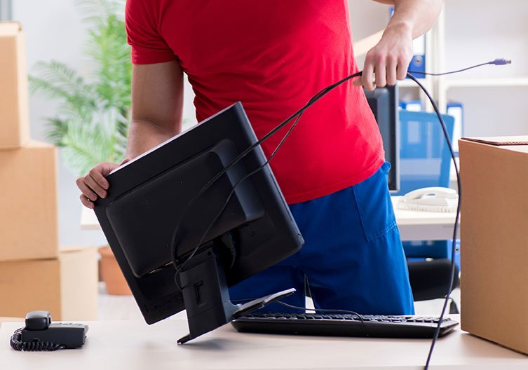 Déménageur qui débranche un écran d'ordinateur