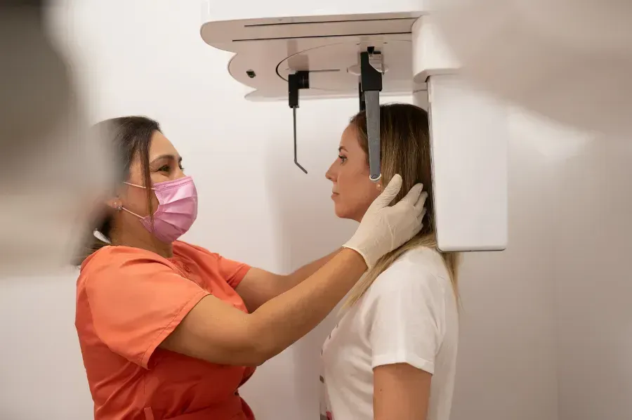 Una enfermera le está haciendo una radiografía de la cara a una mujer.