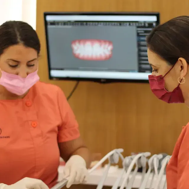 Dos mujeres con mascarillas trabajan en un consultorio dental.