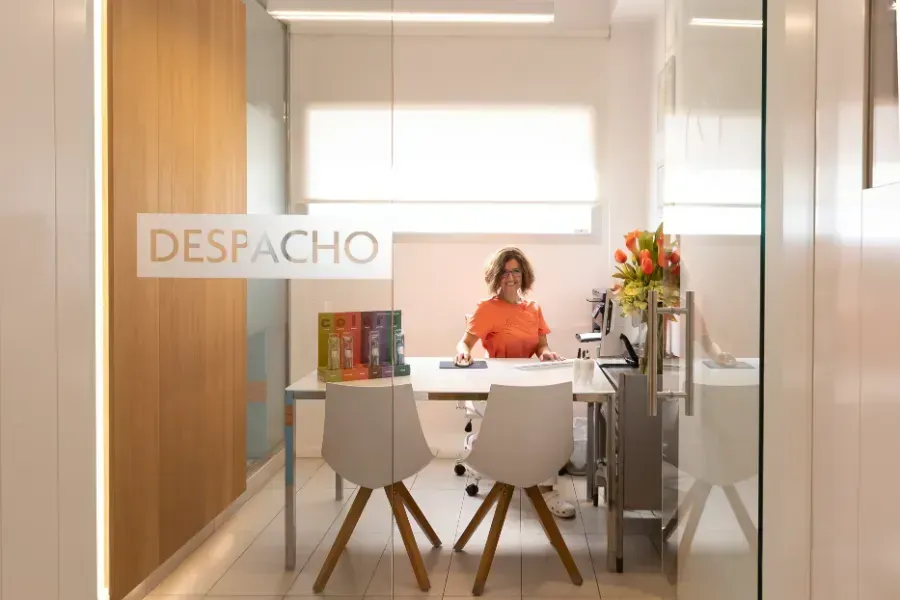 Una mujer está sentada en un escritorio en una oficina de cristal.