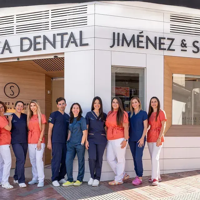 Un grupo de personas de pie frente a un consultorio dental.
