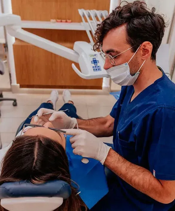 Un dentista con una máscara examina los dientes de un paciente.