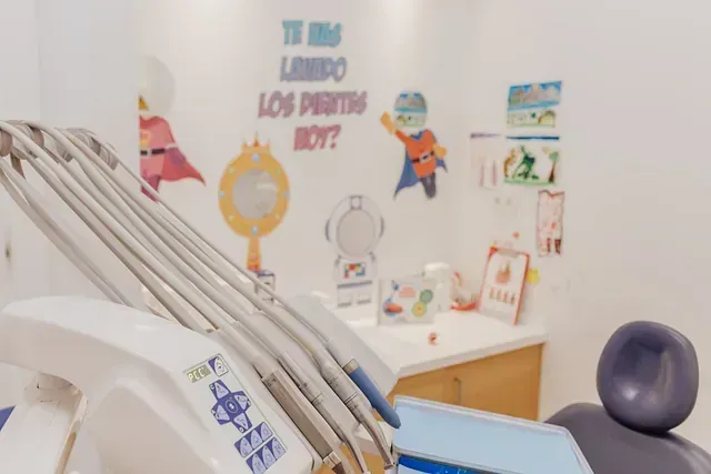 Un consultorio dental con un mural de superhéroe en la pared y una silla dental.