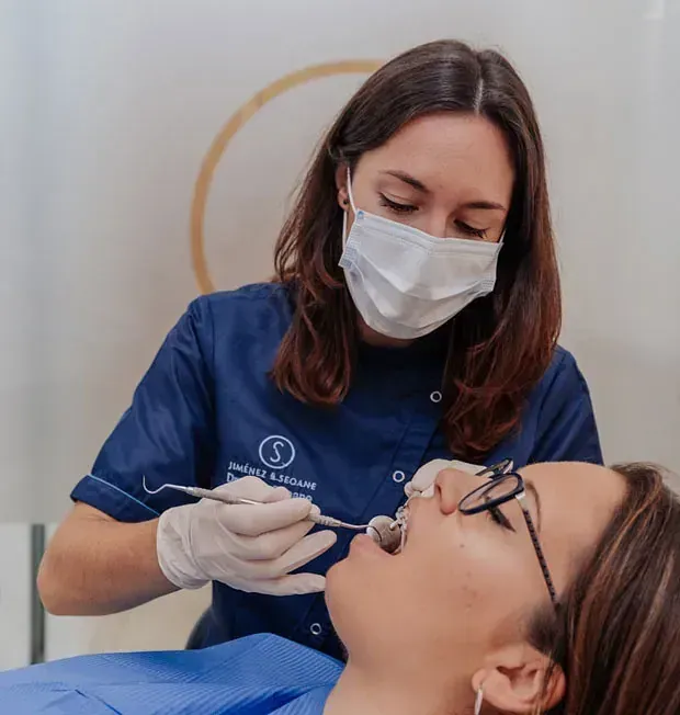 Una mujer se está haciendo examinar los dientes por un dentista.
