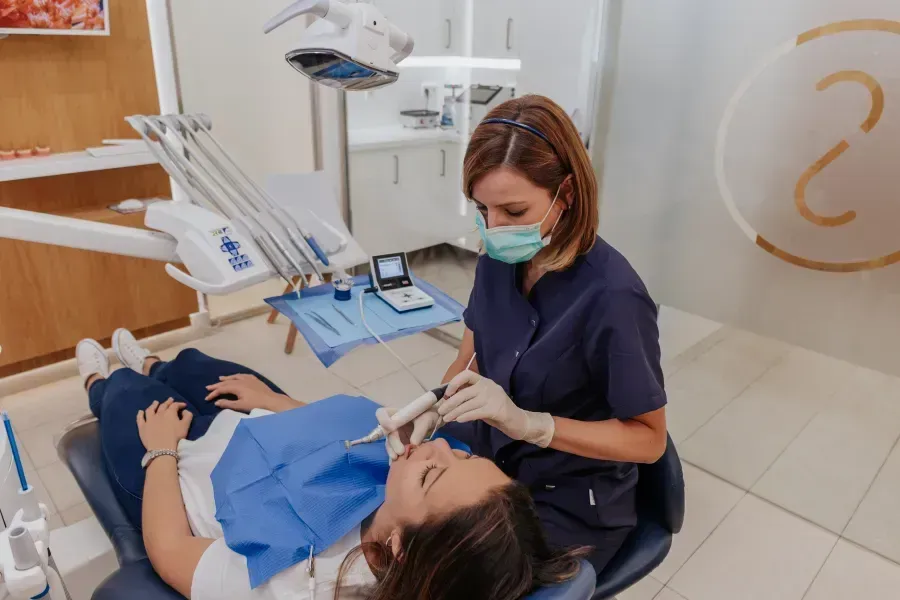 Una mujer está siendo examinada por un dentista en un consultorio dental.