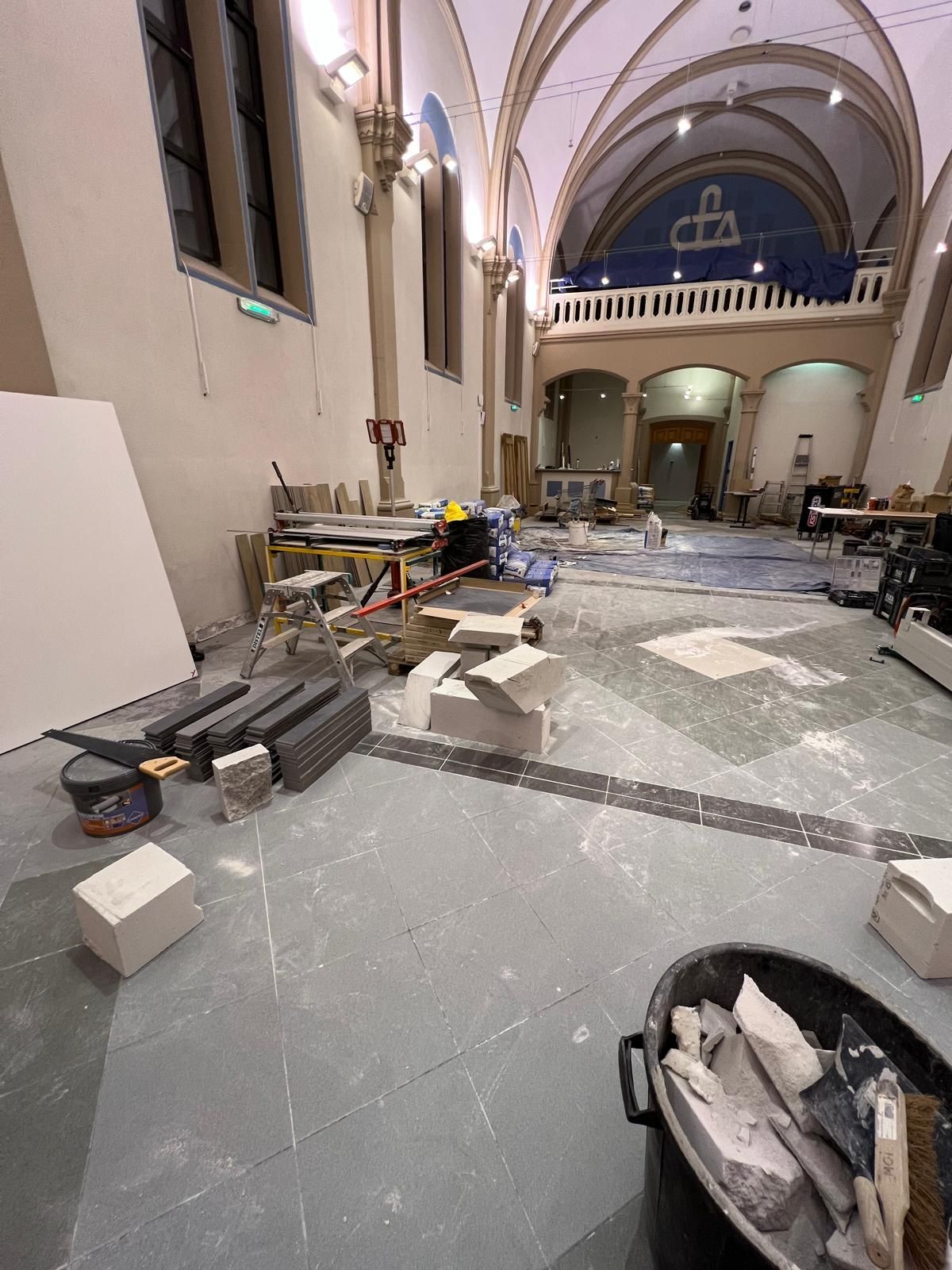 Intérieur d'un bâtiment en rénovation, avec des matériaux de construction éparpillés sur le sol.