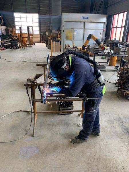 Un homme soude un morceau de métal dans une usine.