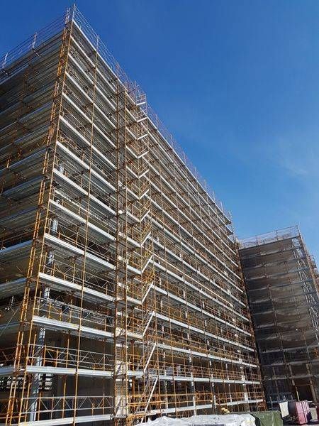 Un grand bâtiment est en cours de construction avec des échafaudages et des escaliers.