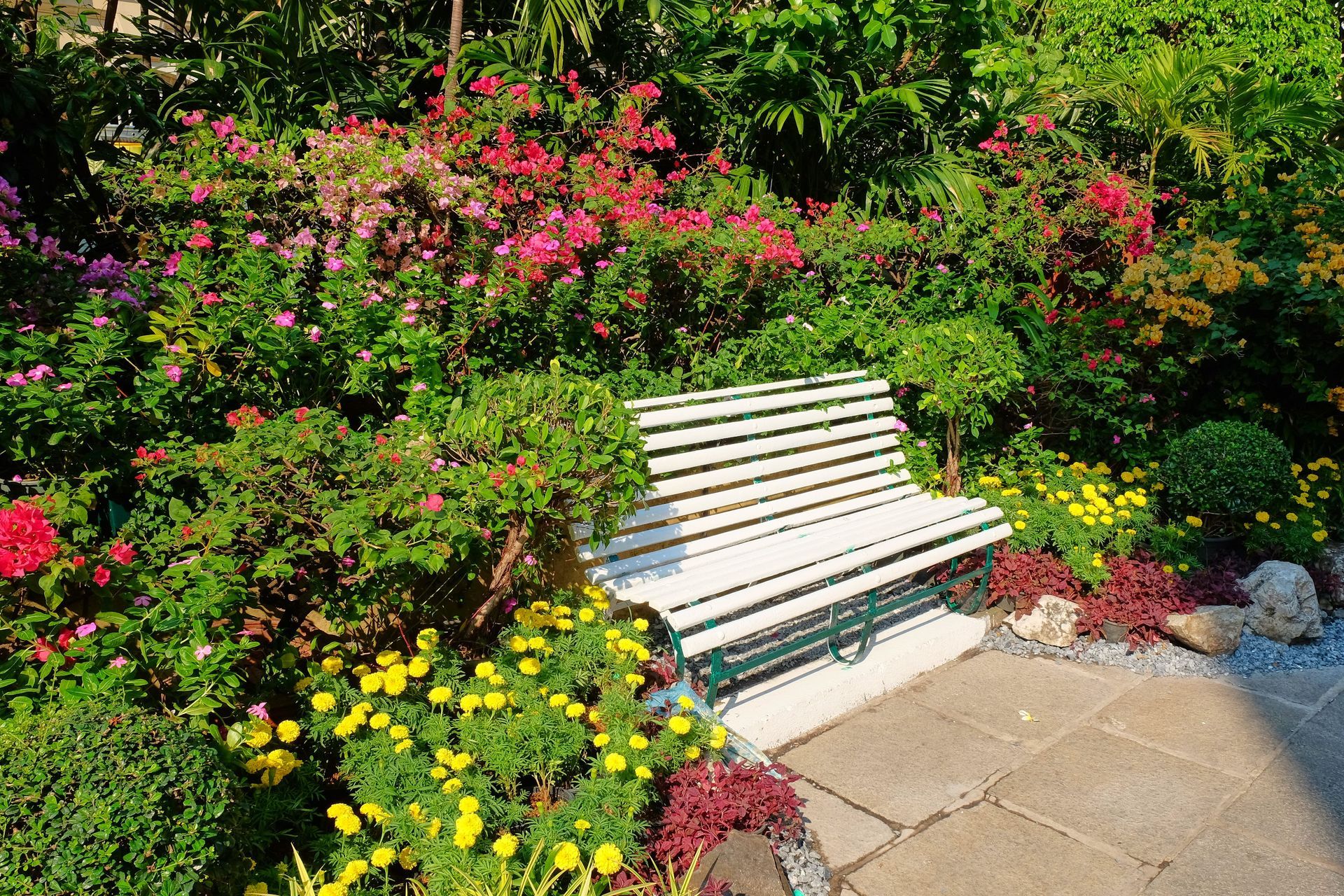 Un banco blanco en un jardín rodeado de flores.