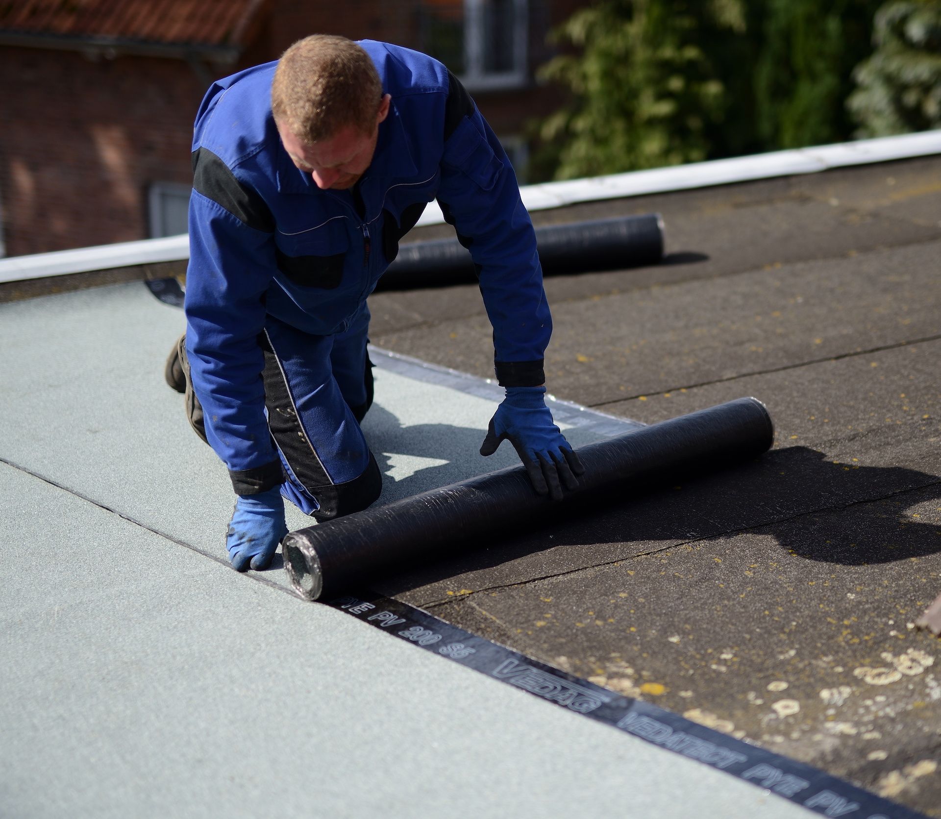 Un ouvrier posant un revêtement sur un toit plat